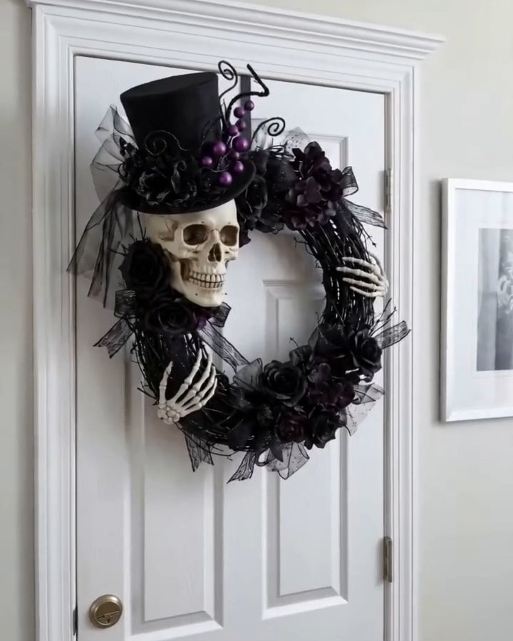 Skeleton skull and black floral details create a gothic diy halloween wreath on a white door