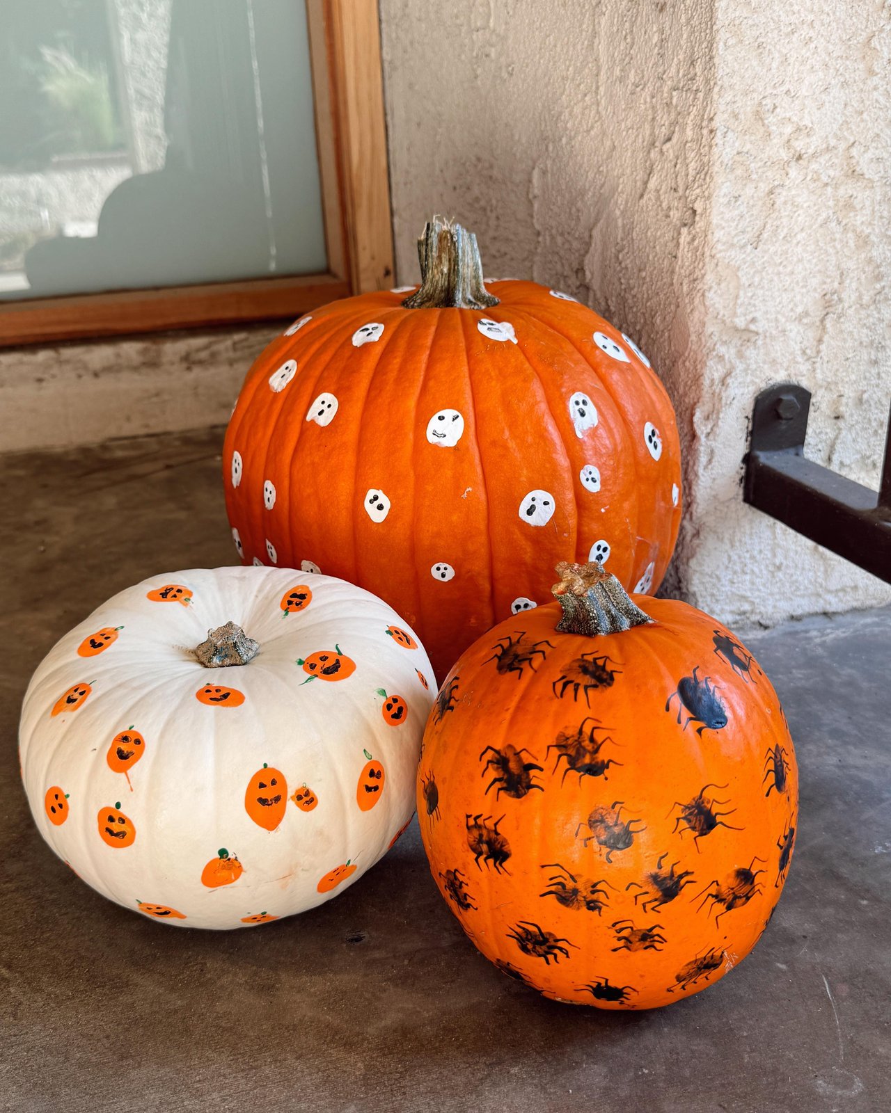 Painted pumpkins with friendly ghosts, jack-o'-lanterns, and spiders for a festive autumn craft display