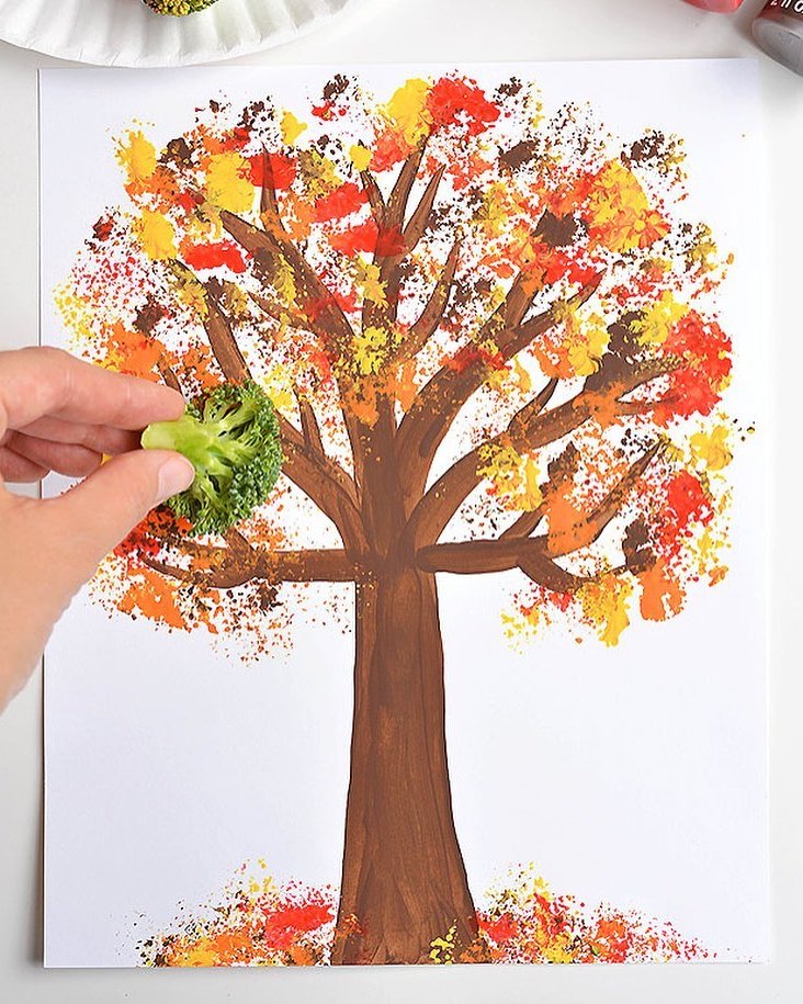 Broccoli-stamped autumn tree art for fall crafts for kids with red, orange, and yellow leaves
