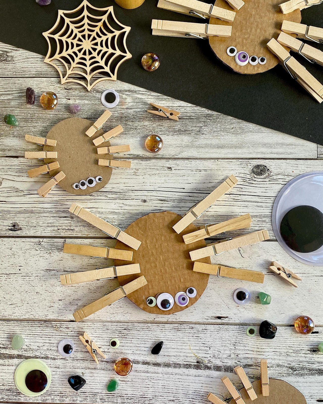 Wooden clothespin spiders, googly eyes, cardboard shapes, and a spiderweb for autumn children's crafts