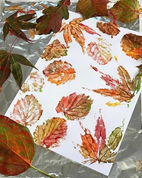 Leaf prints in warm autumn colors on white paper for children's seasonal art