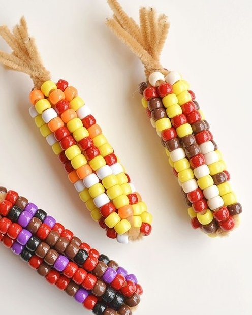 Colorful beaded corn cobs made for fall crafts for kids with warm autumn colors and fuzzy pipe cleaner stems.