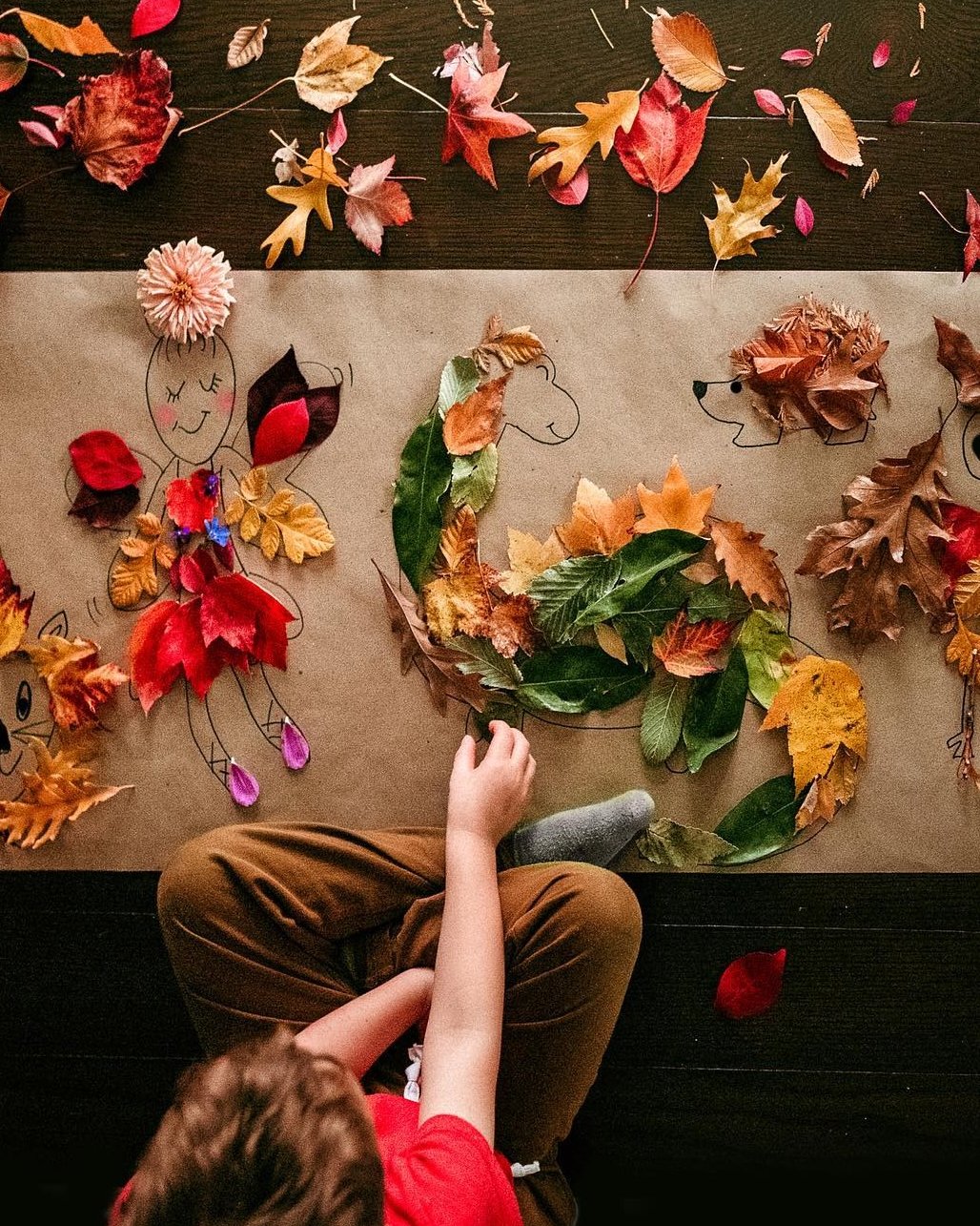 Child creating leaf characters and a leafy hedgehog collage with autumn leaves