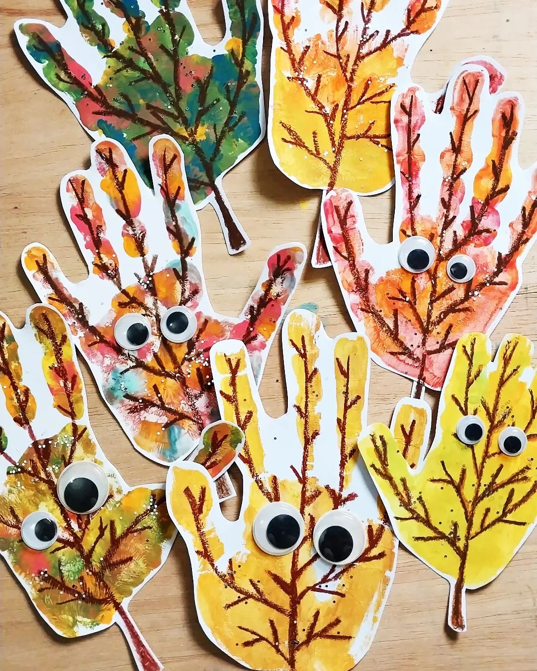 Colorful googly-eyed handprint trees for fall crafts for kids