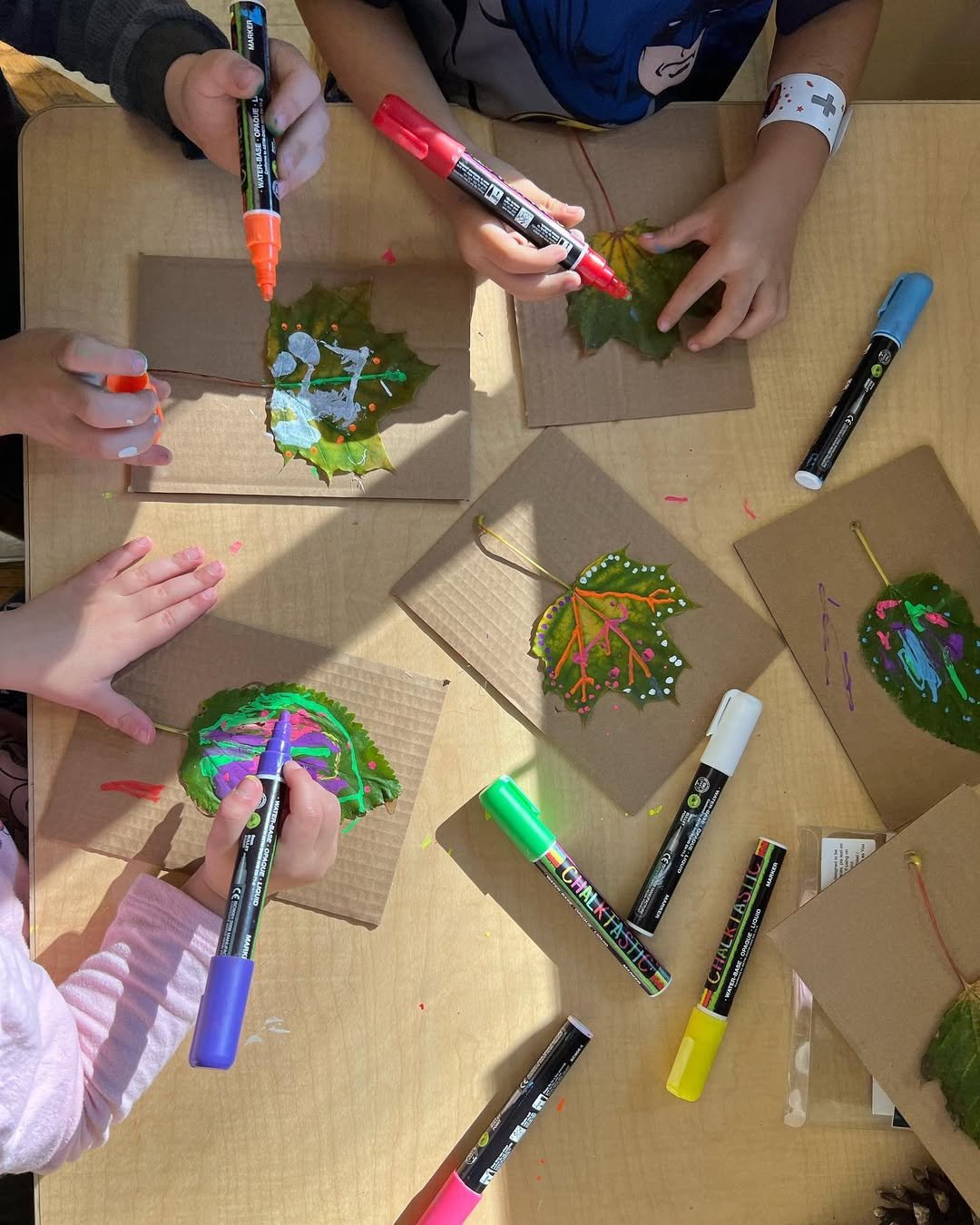 Colorful autumn leaf art made by children with chalk markers on cardboard