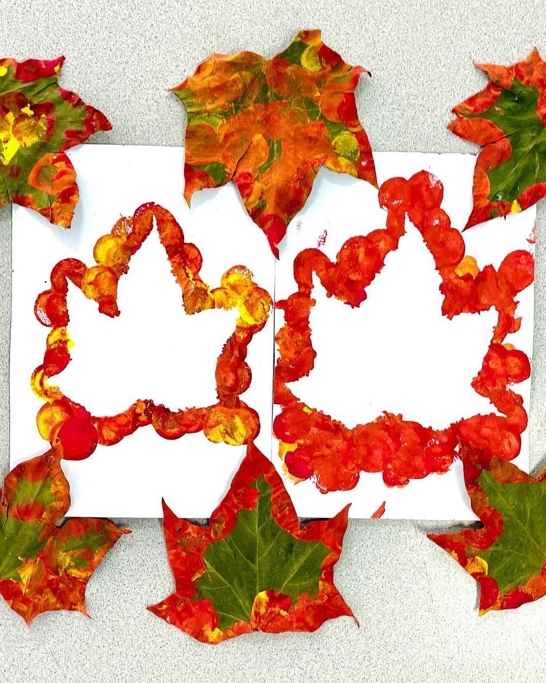 Colorful painted leaves framing white autumn silhouettes on paper