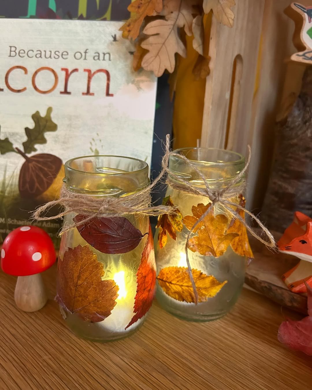 Autumn leaf lanterns glowing inside decorated glass jars with rustic twine