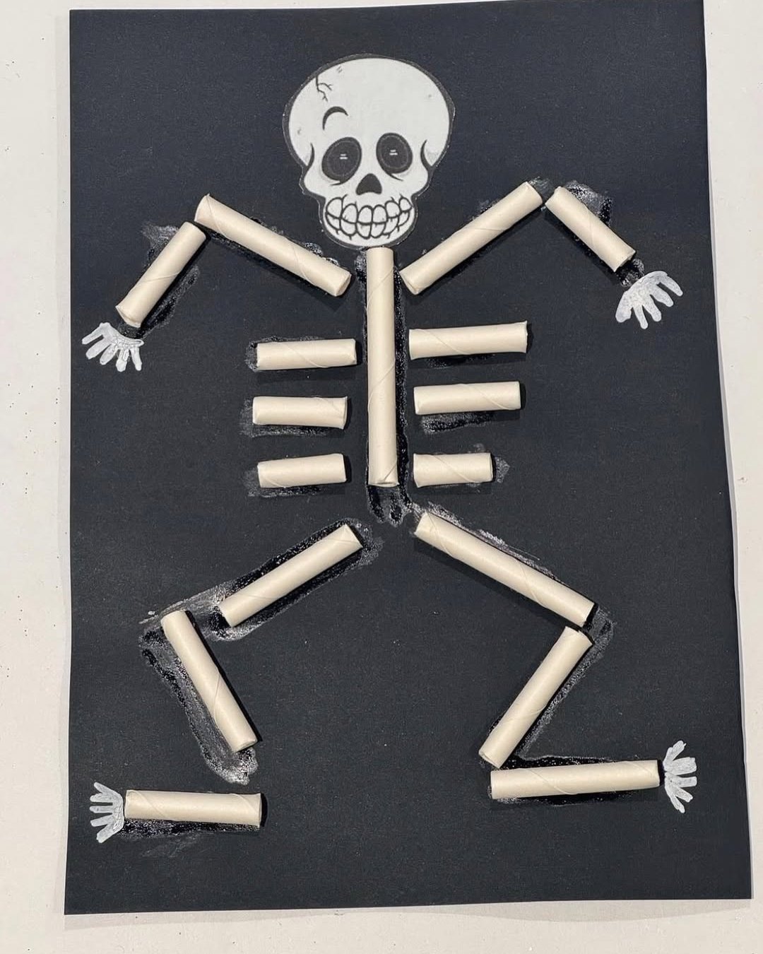 Skeleton craft made from paper rolls on black cardstock for spooky kids' art