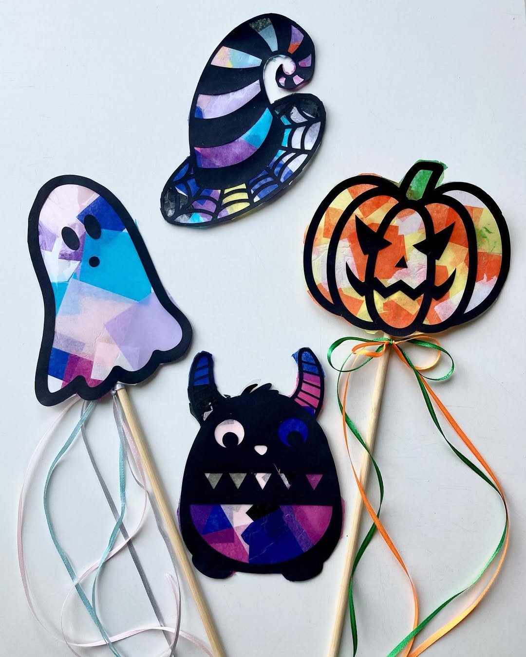 Colorful tissue paper Halloween puppets featuring a ghost, witch hat, pumpkin, and bat