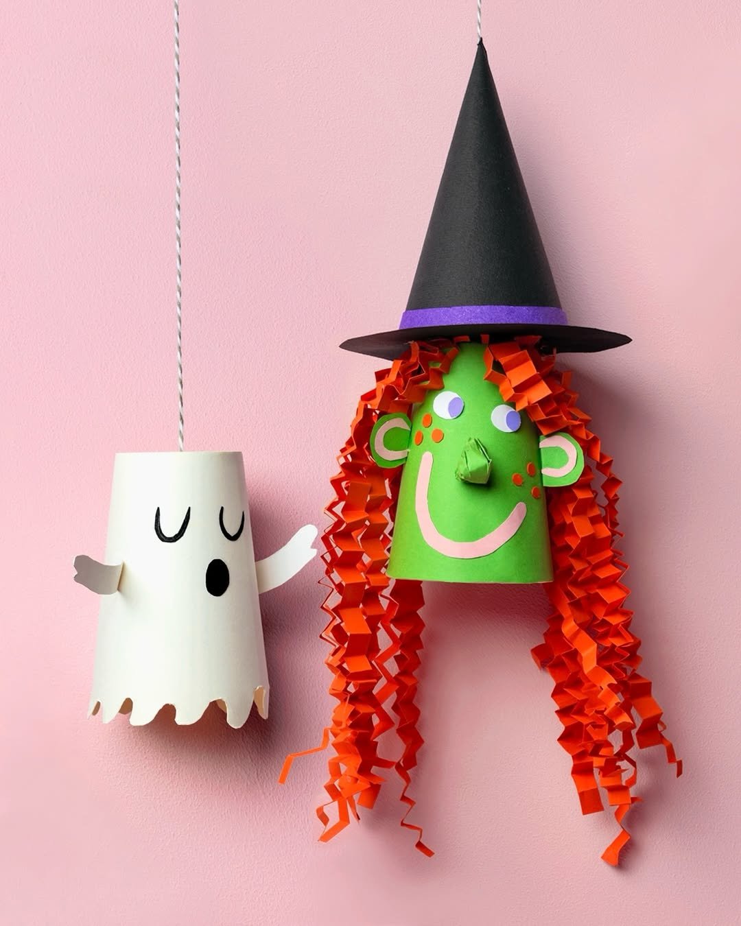 Paper cup witch with curly orange hair beside a hanging ghost for spooky children's crafts