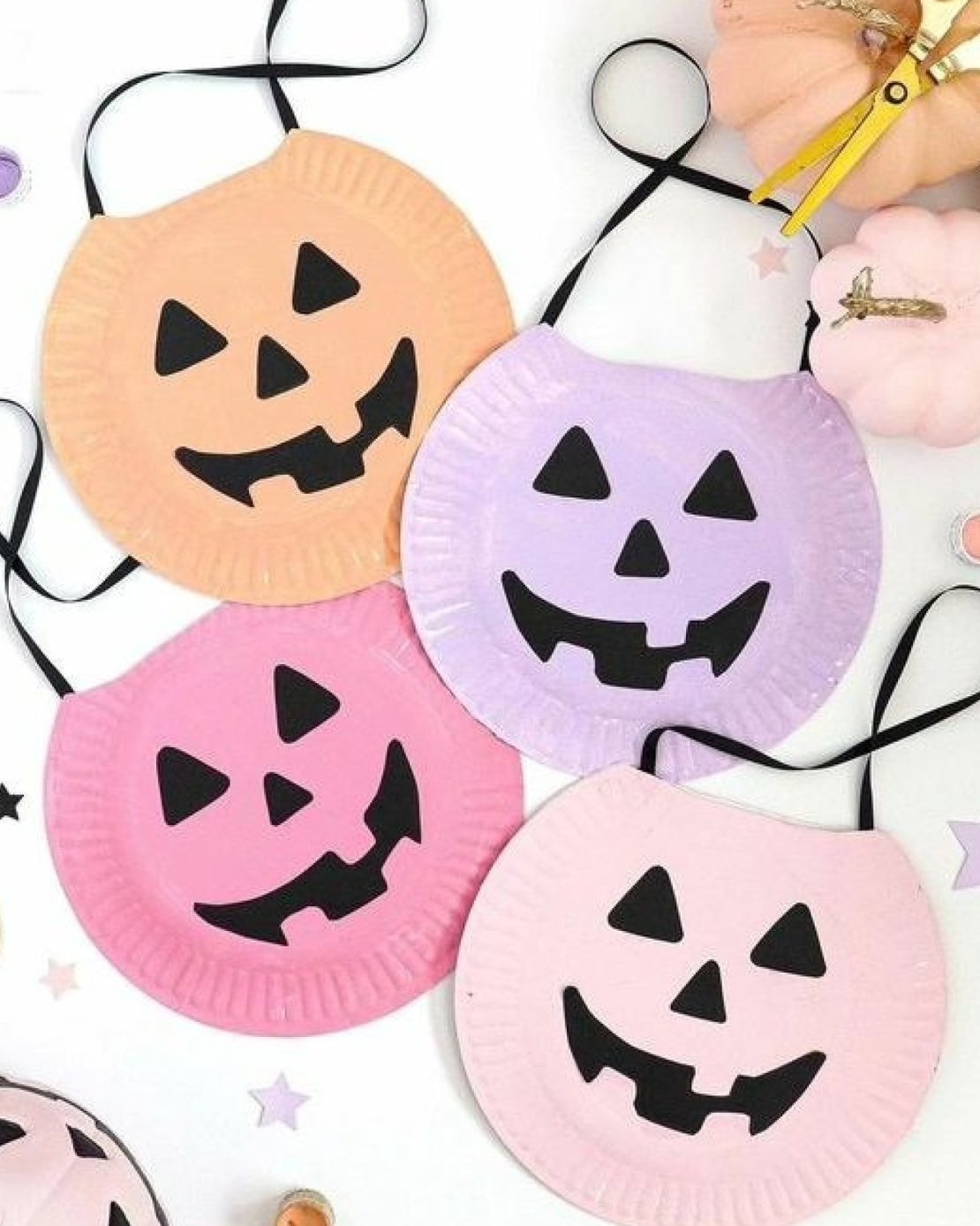 Pastel paper plate pumpkins with black jack-o-lantern faces for children's Halloween crafting