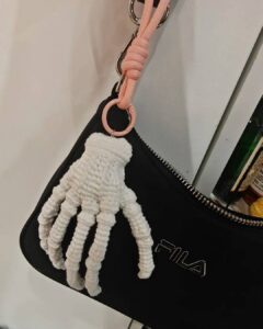 Halloween Crochet Ideas featuring a white crocheted skeleton hand charm on a black pouch
