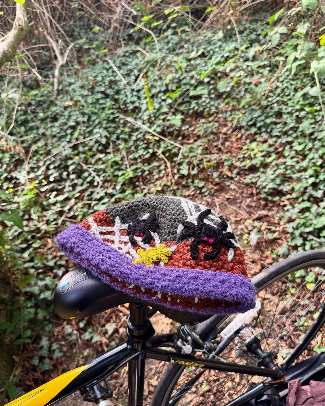 Colorful crocheted bicycle seat cover with spiderwebs, bats, and spooky Halloween details