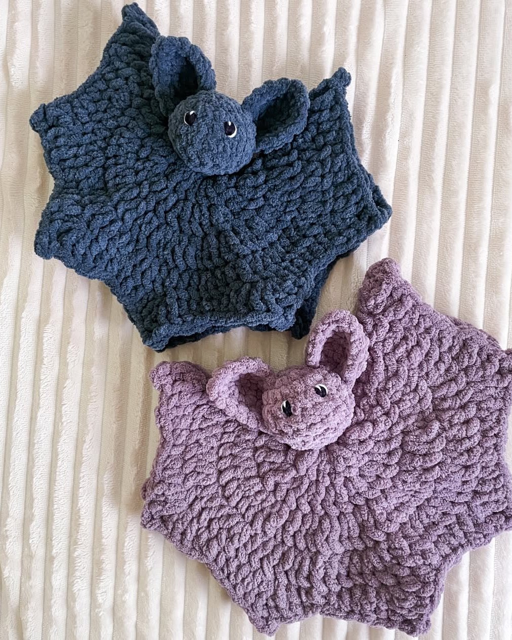 Two textured crocheted bat lovey blankets in navy and lavender for a cozy Halloween craft