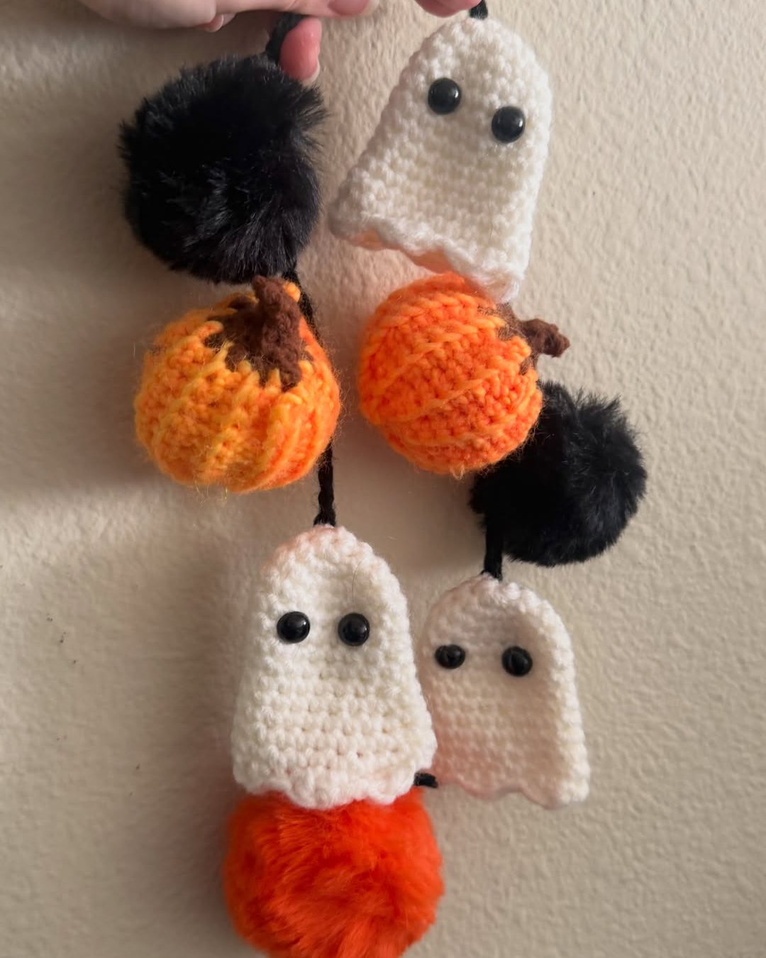 Handmade crochet ghost and pumpkin garland with black pom-poms for festive Halloween decor