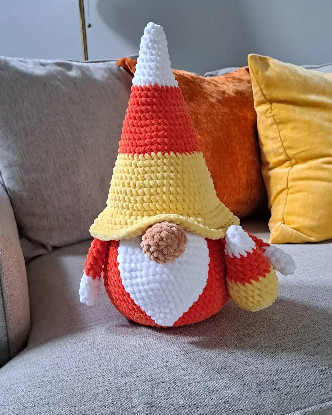 Plush candy corn gnome with a pointed hat for spooky crochet décor