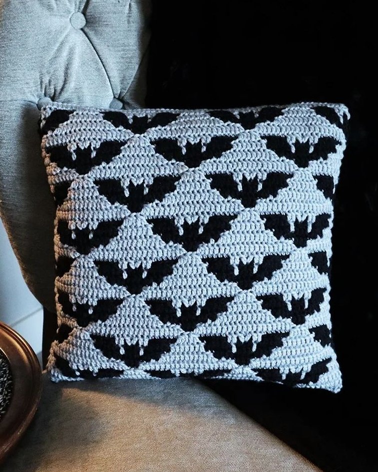Bat crochet pillow with repeating black bat motifs on a textured gray background