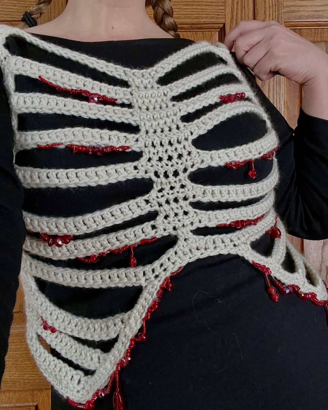 Crochet skeleton rib cage costume wrap with cream yarn, black fabric, and red bead accents