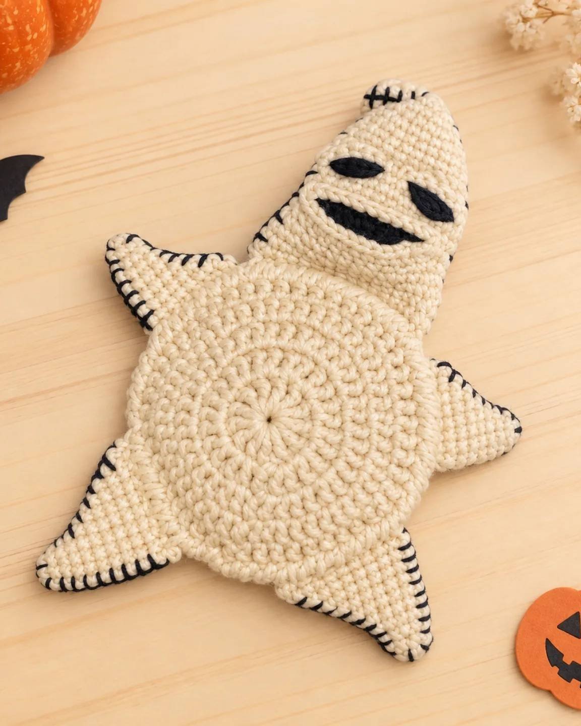 Cream crochet ghost pillow with black stitched features for spooky seasonal decor
