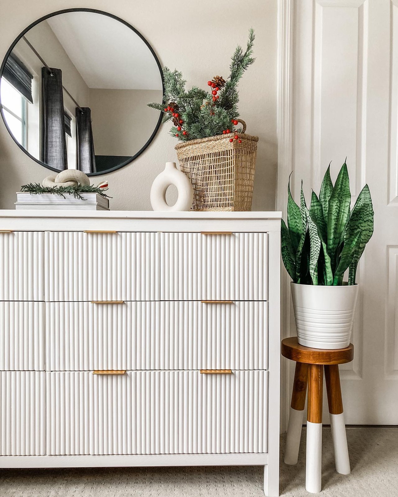 White Hemnes dresser with full fluted drawer fronts, brass pulls, greenery, woven basket, and round mirror