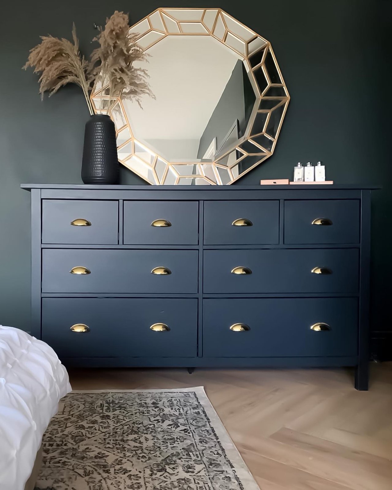 Black-painted Hemnes dresser with gold cup pulls beneath a geometric mirror