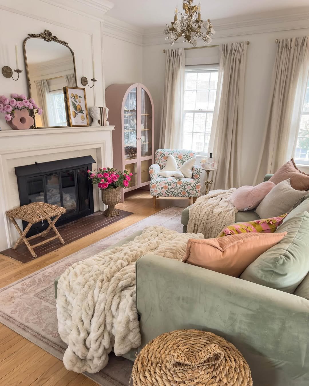 Soft sage sofa with chunky knit throw, fireplace, floral chair, and elegant winter living room accents