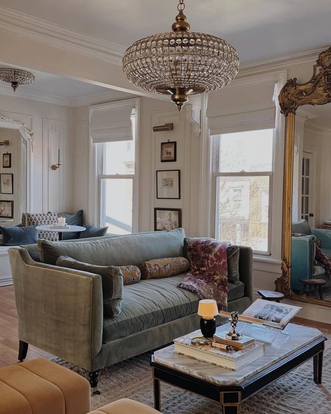 Elegant crystal chandelier illuminating a cozy gray living room with velvet seating and winter accents