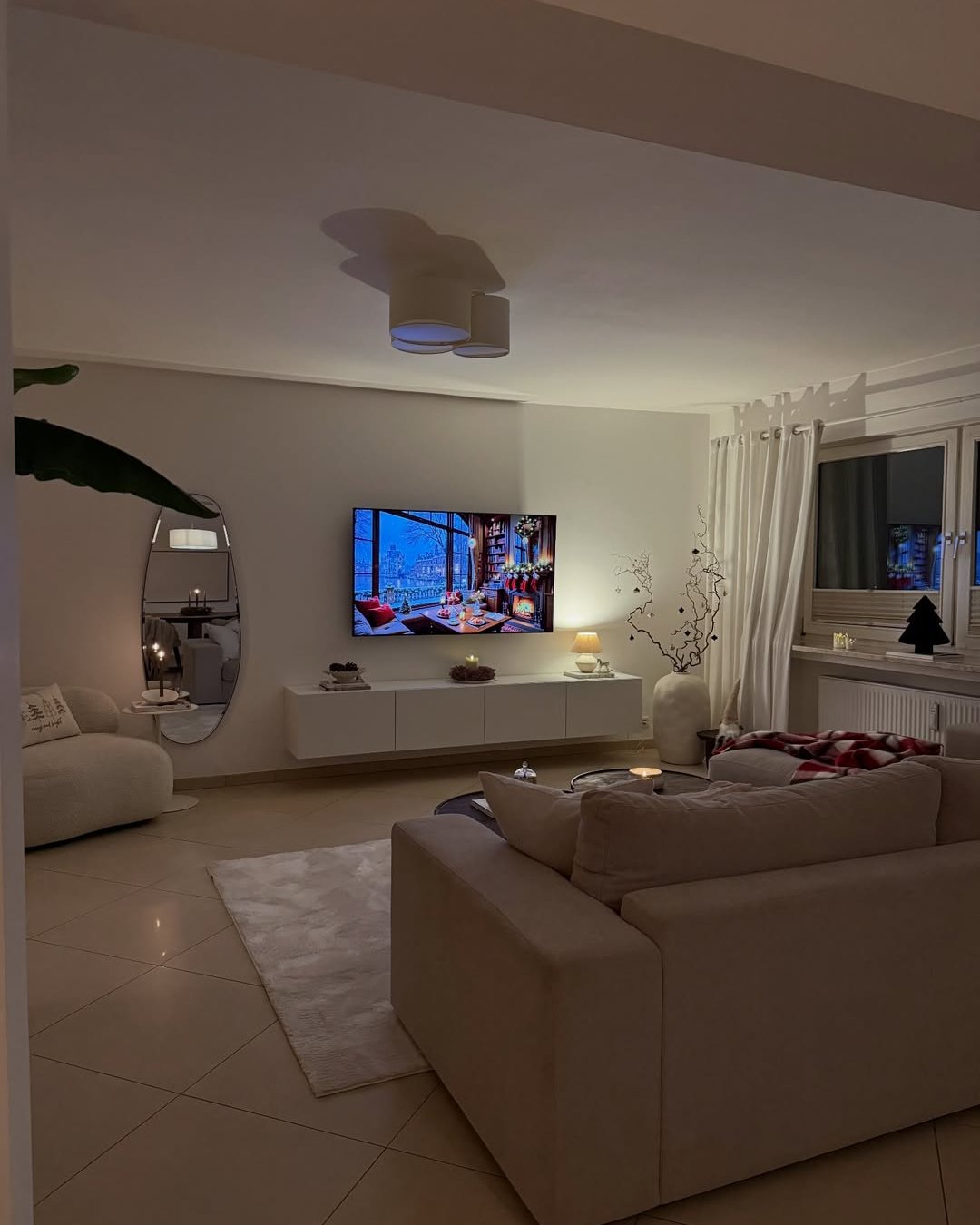 Soft neutral living room with candles, plush seating, plaid throw, and cozy winter accents