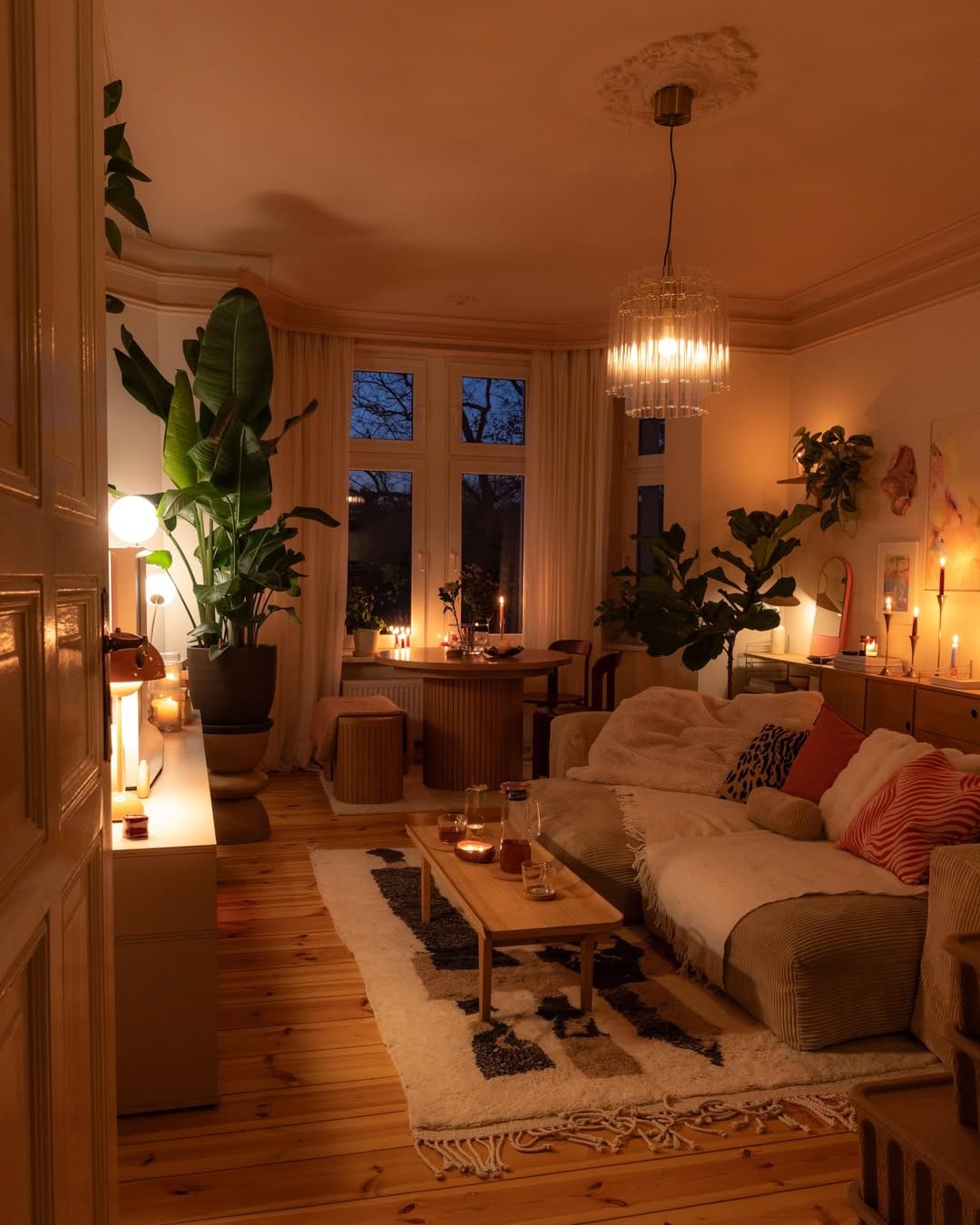 Warm candlelit living room with lush plants, layered throws, and textured winter styling