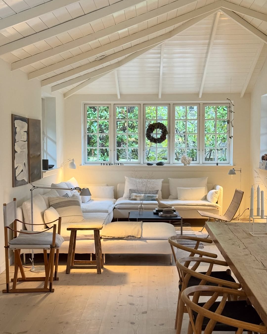 White Scandinavian living room featuring winter living room decor ideas, layered textiles, candles, and an evergreen wreath